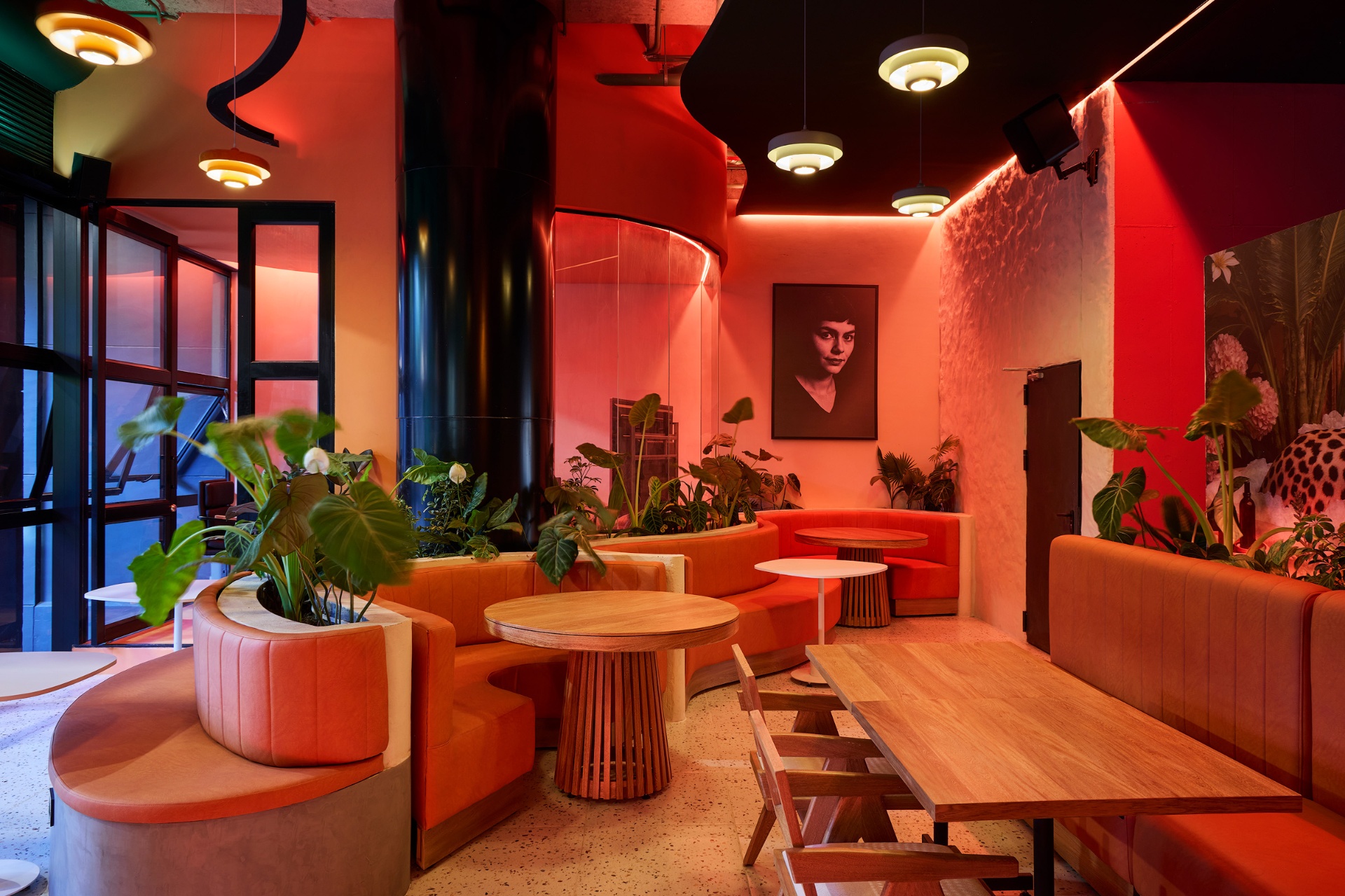 Salón lounge de Amelier Poblado con sofás naranjas curvos y luz cálida