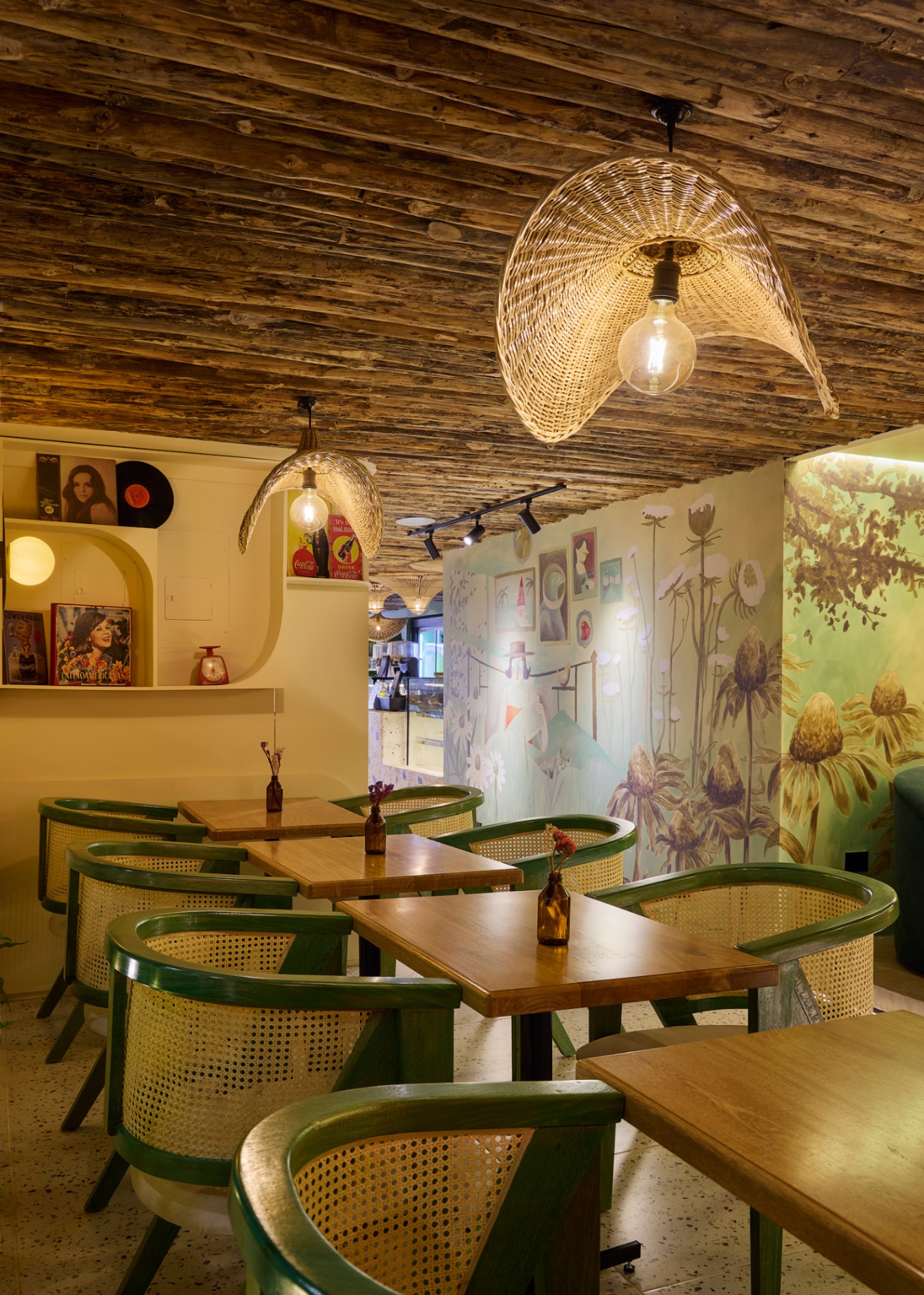 Interior Amelier Laureles con sillas de mimbre verde y mural botánico