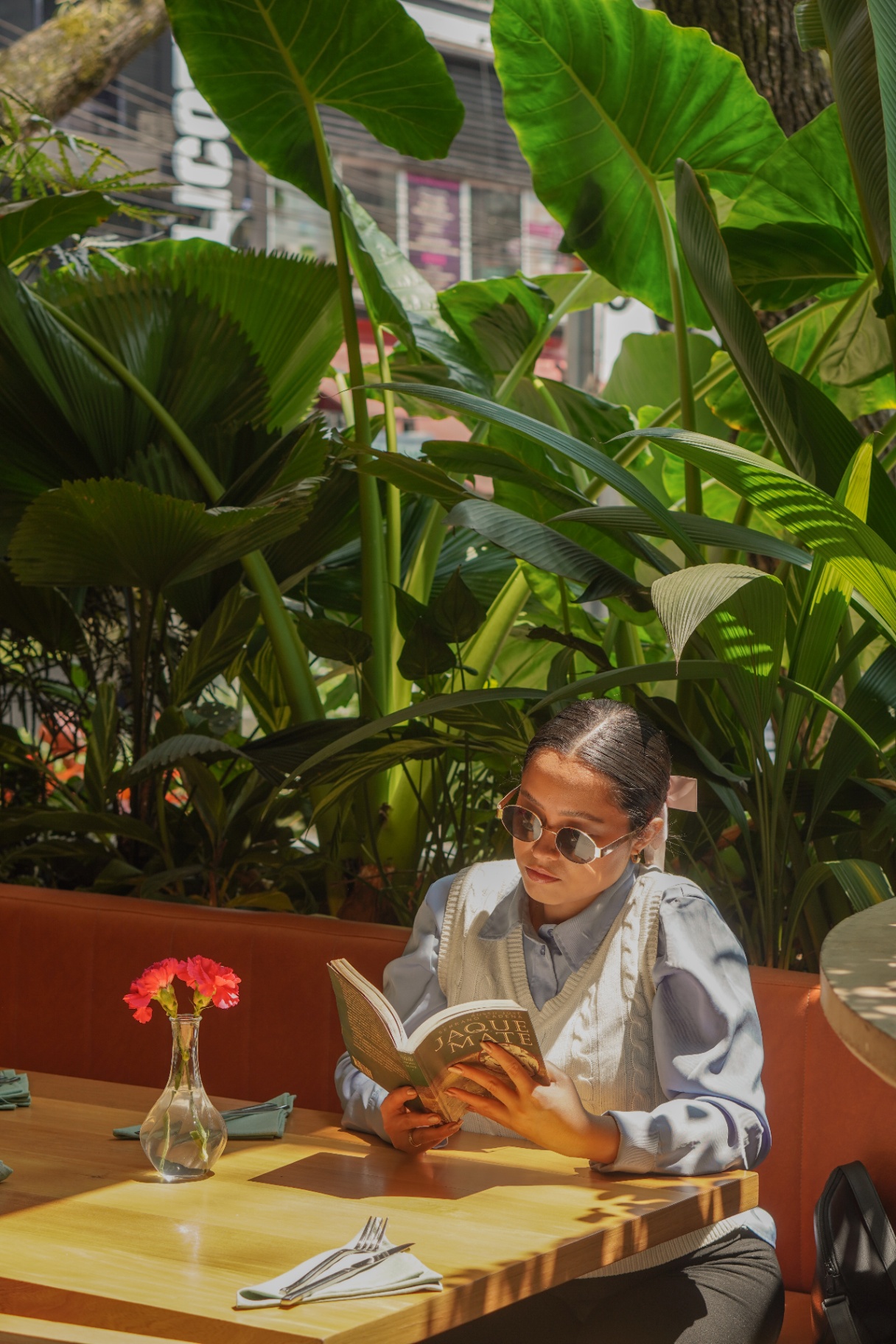 Mujer leyendo entre plantas tropicales en Amelier